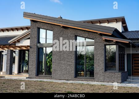 Modernes Haus mit Naturatmosphäre, hölzernen Felsdetails und Pflanzen und großen Fenstern Stockfoto