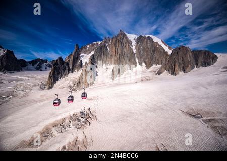 Drei Hütten der Panorama-Seilbahn Mont Blanc, die den Géant-Gletscher, Felsenklippen und den Gipfel des Mont Blanc du Tacul in der Ferne überqueren. Stockfoto