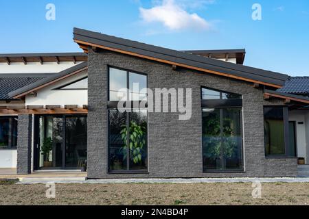 Modernes Haus mit Naturatmosphäre, hölzernen Felsdetails und Pflanzen und großen Fenstern Stockfoto