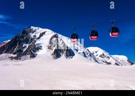 Drei Hütten der Panorama-Seilbahn Mont Blanc, die den Géant-Gletscher, Mont Blanc du Tacul, Mont Blanc und Dome du Goutier in der Ferne überqueren. Stockfoto