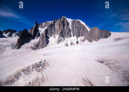 Drei Hütten der Panorama-Seilbahn Mont Blanc, die den Géant-Gletscher, Felsenklippen und den Gipfel des Mont Blanc du Tacul in der Ferne überqueren. Stockfoto