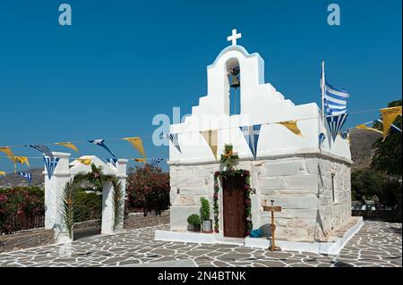 Kleine Kirche mit Blumenreichtum und Flaggen in Parikia, Paros, Kykladen, Griechenland Stockfoto