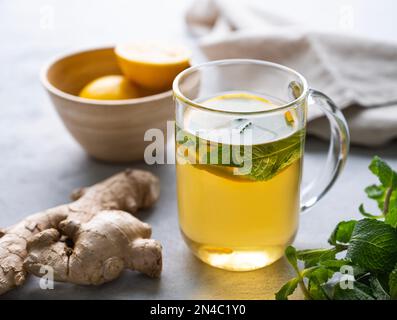 Kräutertee mit frischer Zitrone, Minze und Ingwer auf hellem Hintergrund. Das Konzept eines gesunden Getränks für Immunität. Stockfoto