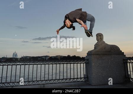 Ein junger Sportler, der in der Stadt Backflip macht. Das Praktizieren von Freerunning. Stockfoto