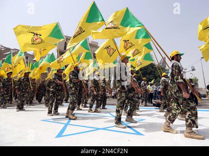 Supporters of Iraqi Hezbollah brigades marching in military uniforms ...