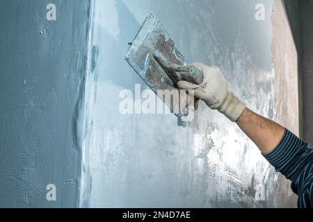 Handarbeit mit einer Kelle zum Abdichten der Wand Stockfoto