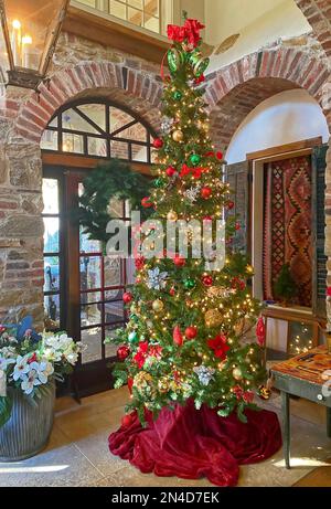 Weihnachtsbaum, hoch, schmal, funkelnde Dekoration, Lichter, Roter Rock, Backsteinbögen, Laterne, Urlaub, festlich, Stockfoto