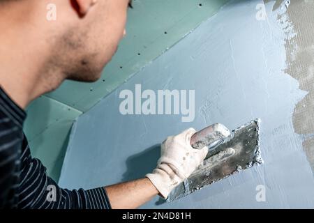 Handarbeit mit einer Kelle zum Abdichten der Wand Stockfoto