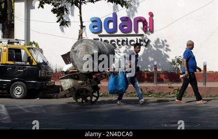 Mumbai, Maharashtra, Indien. 8. Februar 2023. Eine labour schiebt einen Wagen, fährt an einem Adani-Stromschild in Mumbai, Indien, 08. Februar 2023 vorbei.Indiens Adani-Krise breitet sich in Straßenproteste aus, da die Verluste laut einem indischen Medienbericht über 110 Milliarden Dollar liegen. (Kreditbild: © Indranil Aditya/ZUMA Press Wire) NUR REDAKTIONELLE VERWENDUNG! Nicht für den kommerziellen GEBRAUCH! Stockfoto