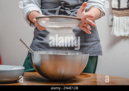 Kochen Sie Mehl durch das Sieb, um Teig zu machen Stockfoto