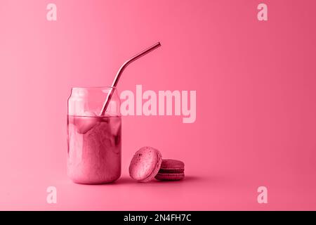 Ein Glas Eiskaffee in einem großen Glas mit Creme und Makronen in trendigen magentafarbenen Farben des Jahres 2023. Speisekonzept. Speicherplatz kopieren. Nahaufnahme. Stockfoto
