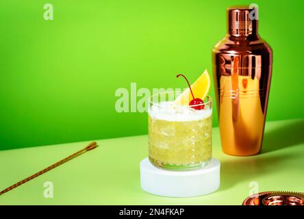 Whiskey Sour Cocktail mit Bourbon, Zitronensaft, Eiweiß und Eis, Steinglas auf grünem Hintergrund Stockfoto