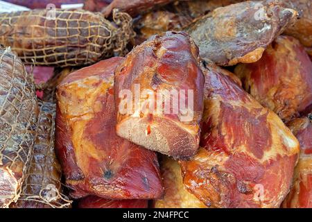 Ein Haufen geräucherter Speck und geräuchertes Schweinefleisch mit Schinken, das an einem lokalen Marktstand verkauft wird Stockfoto