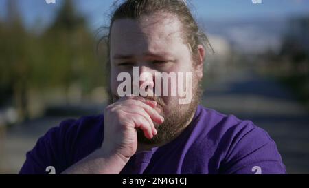 Besorgter junger Mann, der draußen steht und Angst hat. Nahaufnahme des Gesichts bei übergewichtigem Mann mit beunruhigtem Gesichtsausdruck Stockfoto