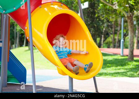 Klettern und Rutschen für Kinder auf dem Spielplatz im Freien. Kinder spielen im sonnigen Sommerpark. Aktivitäts- und Vergnügungszentrum im Kindergarten oder Schulhof. Stockfoto