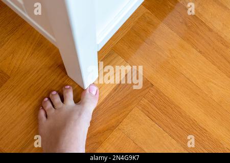 Eine Frau hat die Möbel mit einem großen Zeh getroffen. Vorfall zu Hause. Verletzung des Fusses Stockfoto