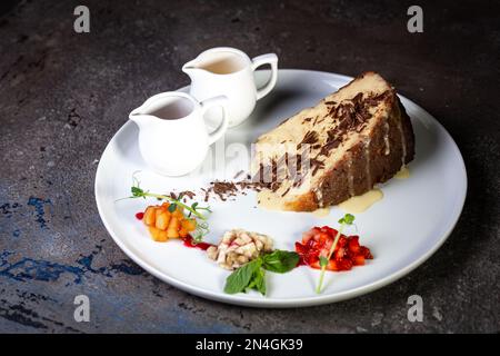 Dessertschwammkuchen mit Kondensmilch und Schokoladenstückchen auf einem weißen Teller Stockfoto