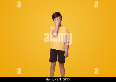 Ein junger Kaukasier, der Hand aufs Gesicht legt, ein epischer Gesichtsschmerz, isoliert auf einem Studioporträt mit gelbem Hintergrund. Das Konzept des Lebensstils der Menschen Stockfoto