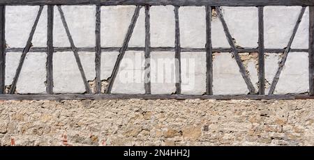 Ruinöse Fachwerkhölzer über einer alten Steinmauer Stockfoto