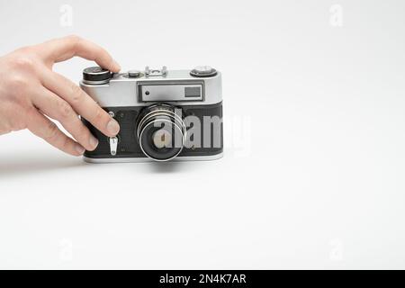 Hand drückt die Aufnahmetaste einer Oldtimer-Filmkamera, isoliert auf weißem Hintergrund. Hand fotografiert mit einer alten Filmkamera. Mit dem Finger auf drücken Stockfoto