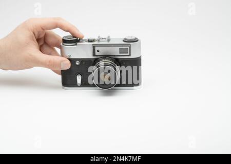 Hand drückt die Aufnahmetaste einer Oldtimer-Filmkamera, isoliert auf weißem Hintergrund. Hand fotografiert mit einer alten Filmkamera. Mit dem Finger auf drücken Stockfoto