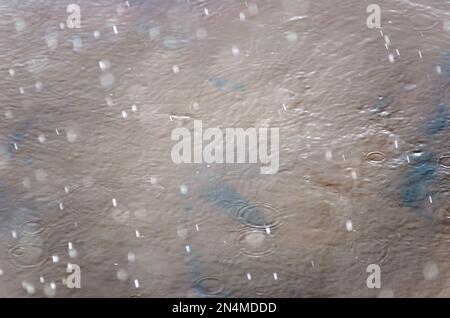 Fotos von Hagel- und Regenfällen mit hoher Geschwindigkeit werden auf der Wasseroberfläche des Flusses mit Kreisen im Herbst gezeigt. Stockfoto