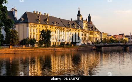 Wroclaw, Polen - 19. Juli 2022: Historisches Altstadtviertel mit Universität Wroclaw und Grodzka Straßendamm bei Sonnenuntergang über dem Fluss Warta Stockfoto