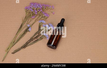 Blumenarrangements und Tropfflasche. Getrocknetes Blumenmuster auf Papierhintergrund. Nach oben und flach verlegt. Stockfoto