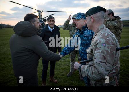 Lulworth, Vereinigtes Königreich. 08. Februar 2023. Der britische Premierminister Rishi Sunak, rechts, und der ukrainische Präsident Volodymyr Zelenskyy, links, werden bei der Ankunft im Bovington Camp Armour Centre am 8. Februar 2023 in Lulworth, Dorset, Großbritannien, von ukrainischen und britischen Offizieren begrüßt. Sunak und Zelenskyy besuchten ukrainische Soldaten, die von der britischen Armee auf Challenger-2-Panzern ausgebildet wurden. Kredit: Pool Photo/Pressestelle Des Ukrainischen Präsidenten/Alamy Live News Stockfoto