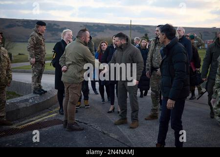 Lulworth, Vereinigtes Königreich. 08. Februar 2023. Der ukrainische Präsident Volodymyr Zelenskyy, Mitte, schüttelt einem ukrainischen Soldaten die Hand, während der britische Premierminister Rishi Sunak bei einem Besuch im Bovington Camp Armour Centre am 8. Februar 2023 in Lulworth, Dorset, Vereinigtes Königreich, zusieht. Sunak und Zelenskyy besuchten ukrainische Soldaten, die von der britischen Armee auf Challenger-2-Panzern ausgebildet wurden. Kredit: Pool Photo/Pressestelle Des Ukrainischen Präsidenten/Alamy Live News Stockfoto