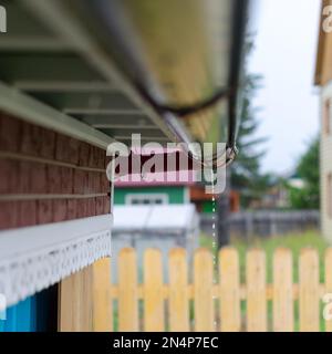 Der Boden der Rinne unter dem Dachrand im neuen Haus des ländlichen Yakutia mit Regentropfen bei nassem Wetter. Sammlung von Trinkwasser von t Stockfoto