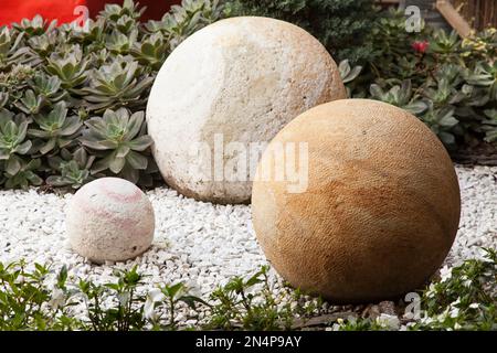 Runde Steine in verschiedenen Größen und Farben schmücken den Garten. Stockfoto