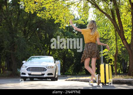 Frau mit Koffer, Taxi auf der Straße, Rückansicht Stockfoto