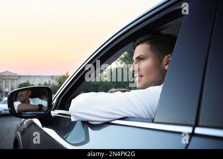 Attraktiver Mann in seinem modernen Auto, Blick von draußen Stockfoto