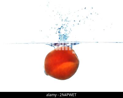Frischer, reifer Pfirsich, der in Wasser auf weißem Hintergrund fällt Stockfoto