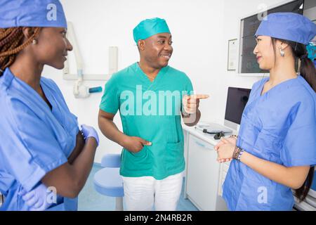 Drei Ärzte, die sich bei der Arbeit unterhalten, multiethnische Gruppen, Gesundheitspersonal Stockfoto