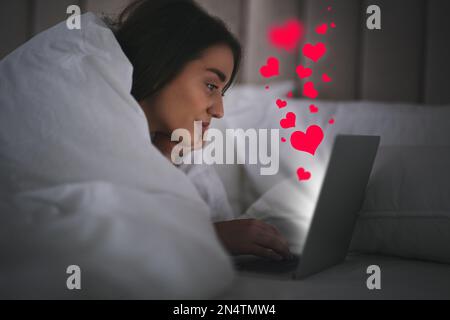 Junge Frau besucht Dating-Seite über Laptop im Haus Stockfoto