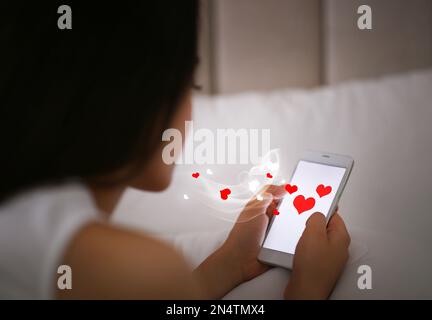 Junge Frau besucht Dating-Seite über Smartphone im Haus Stockfoto