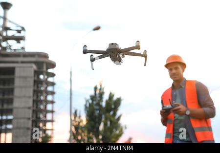 Bauarbeiter, die Drohne mit Fernsteuerung auf der Baustelle bedienen. Luftaufnahmen Stockfoto