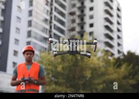 Bauarbeiter, die Drohne mit Fernsteuerung auf der Baustelle bedienen. Luftaufnahmen Stockfoto