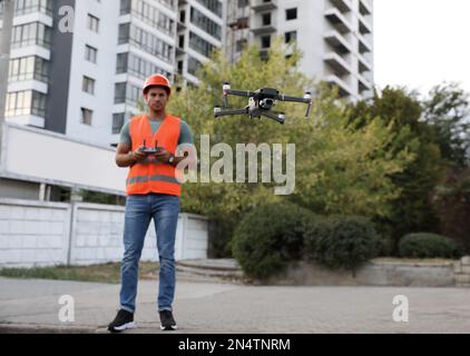 Bauarbeiter, die Drohne mit Fernsteuerung auf der Baustelle bedienen. Luftaufnahmen Stockfoto