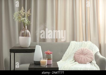 Aroma-Öl-Diffusor und Kerze auf dem Tisch im Raum Stockfoto