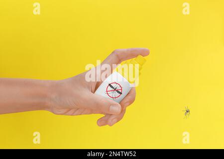 Frau, die Insektenschutzmittel auf Mücken auf gelben Hintergrund spritzt, Nahaufnahme Stockfoto