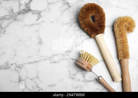 Reinigungsbürsten auf weißem Marmortisch, flach liegend mit Platz für Text. Geschirrspülmittel Stockfoto