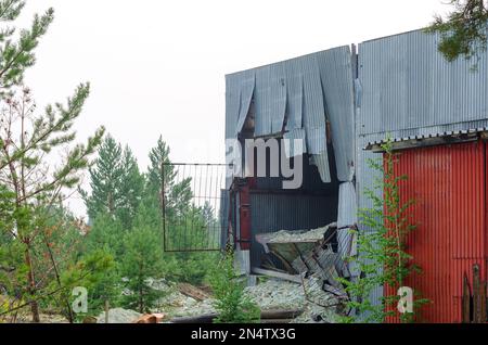 Das Loch in der Metallwand des Hangars der Fabrik, weil die Leiche in der Fabrik in Nord-Yakutia aus dem LKW ragte. Stockfoto