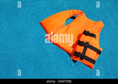 Im Swimmingpool schwimmende, orange Schwimmweste Stockfoto