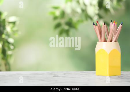 Farbenfrohe Bleistifte im Halter auf weißem Marmortisch. Platz für Text Stockfoto