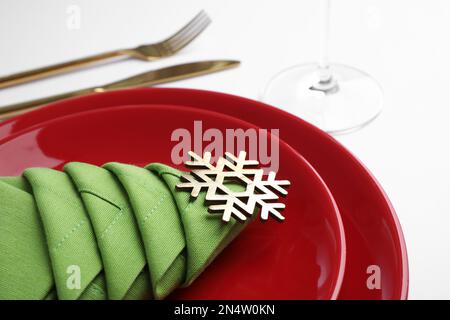 Festliche Tischgestaltung mit grüner Serviette, gefaltet in Form eines Weihnachtsbaums auf weißem Hintergrund, Nahaufnahme Stockfoto