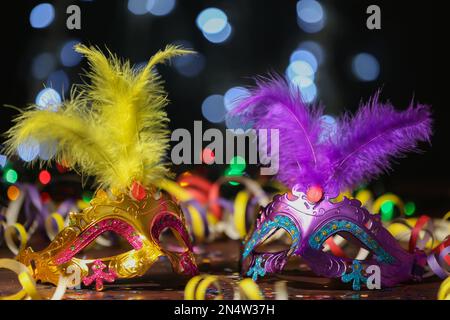 Wunderschöne Karnevalsmasken und Partydekor auf dem Tisch vor verschwommenem Licht Stockfoto