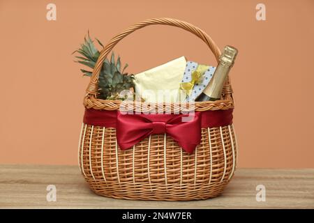 Korb aus Korb mit Ananas und Flasche Champagner auf Holztisch Stockfoto